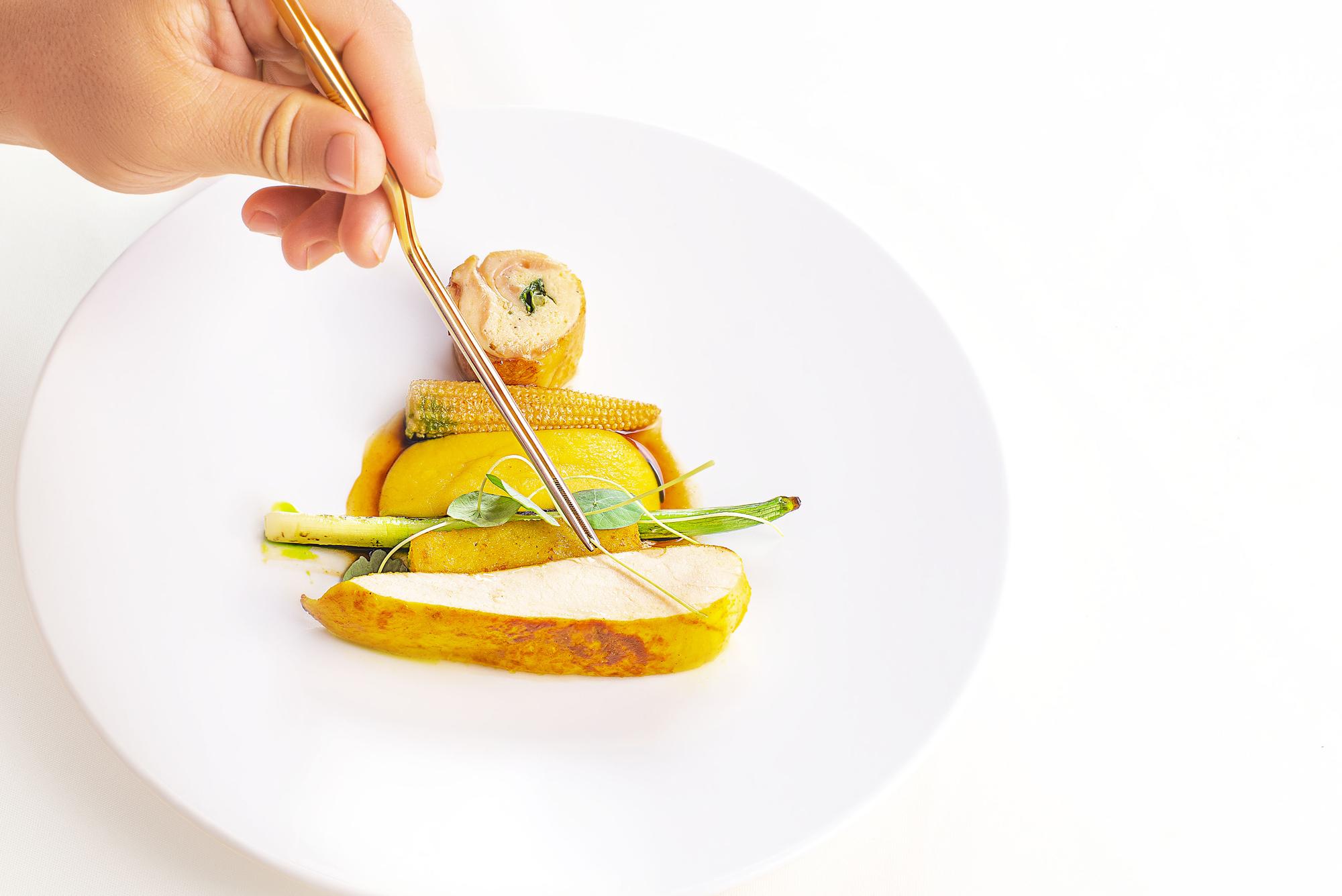 Chef arranging plated dish in bright kitchen